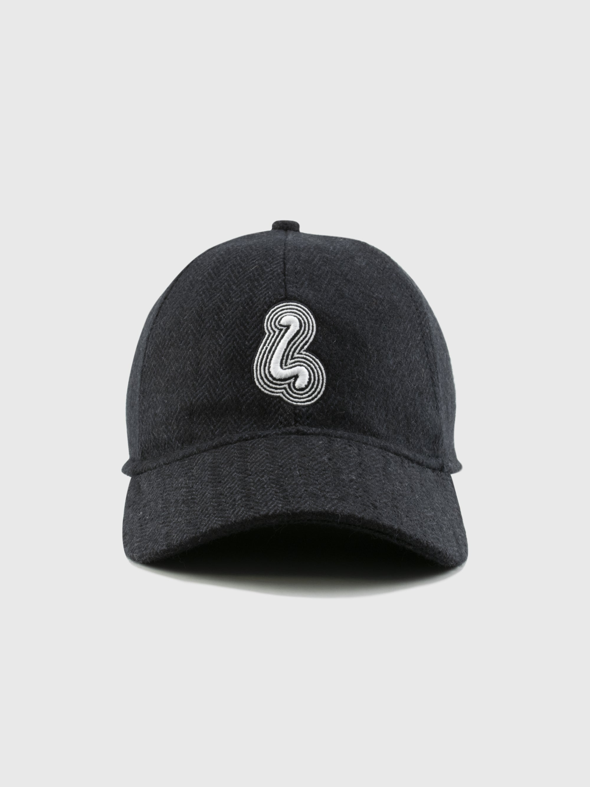 Gray herringbone wool cap with a white logo on a light gray background.