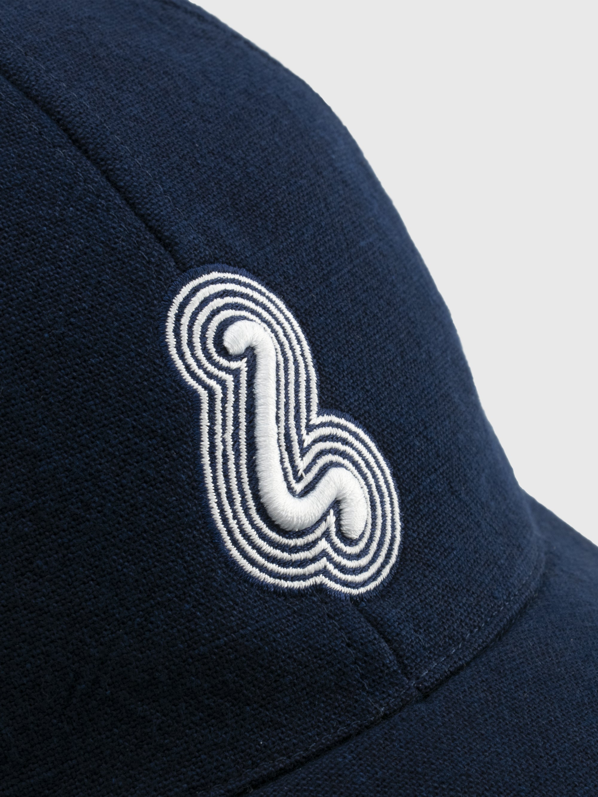 Navy blue cap with a white embroidered logo on a light gray background