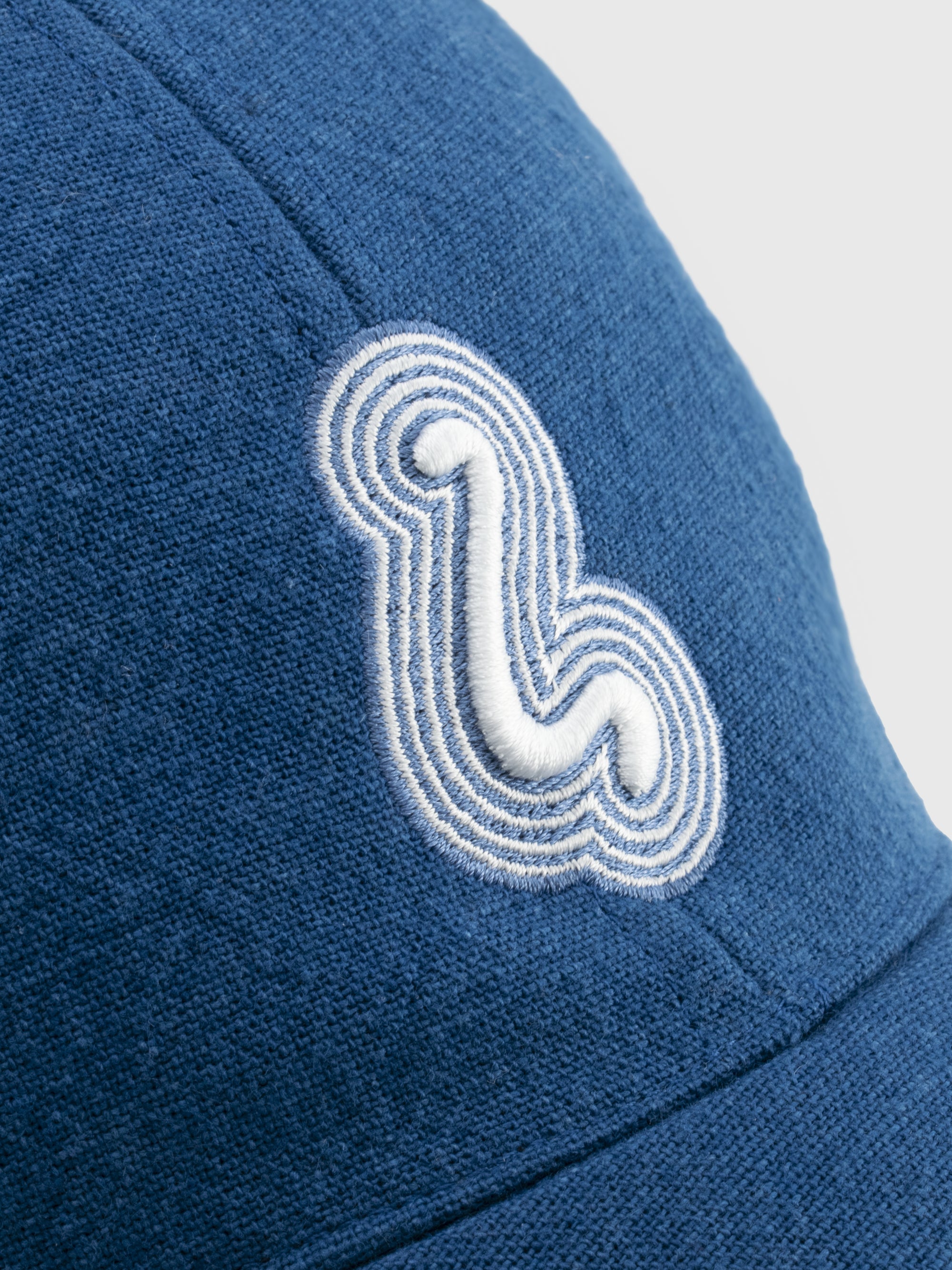 Blue cap with a white embroidered logo on a light gray background