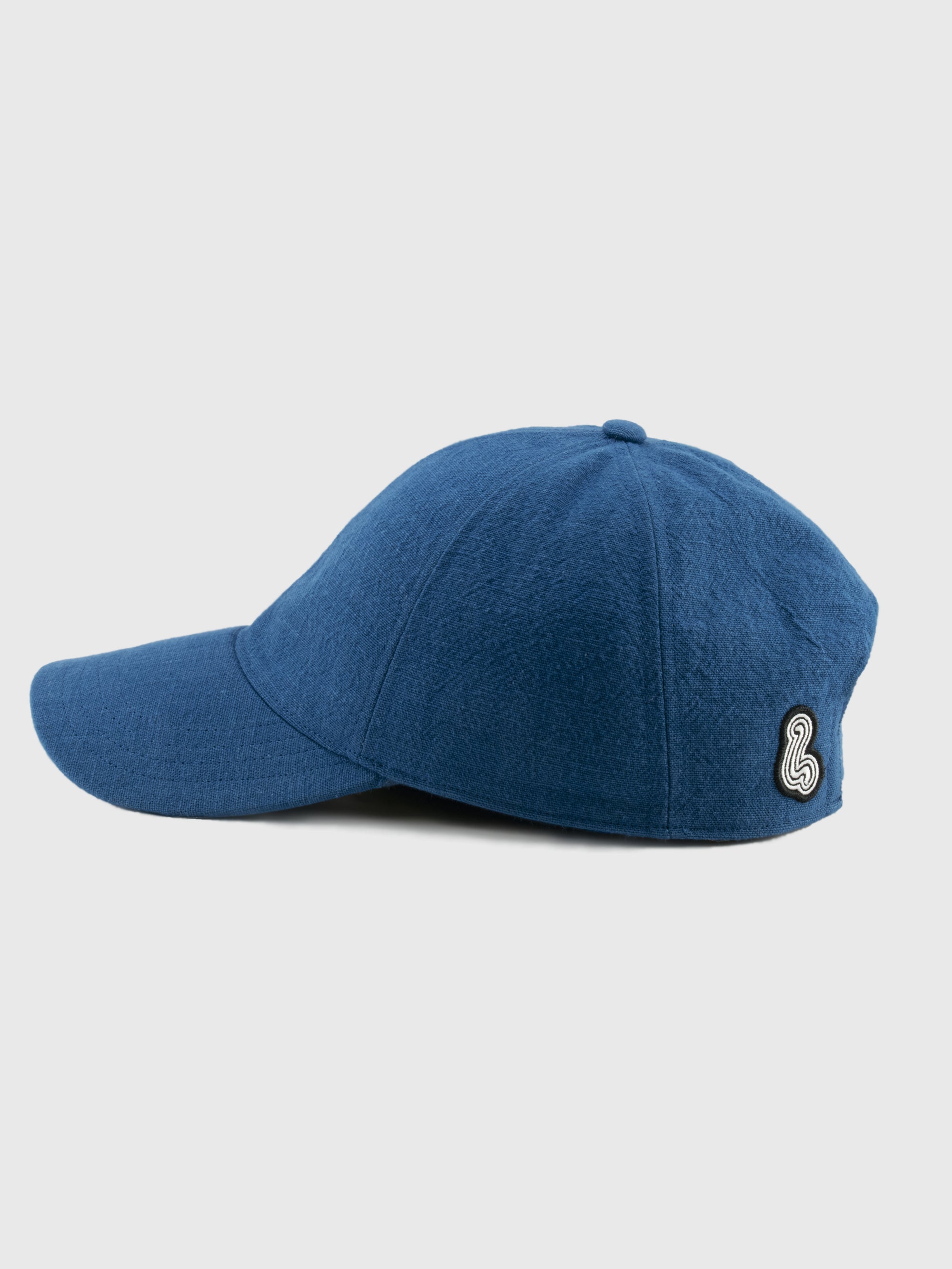 Blue cap with a logo patch on a light gray background