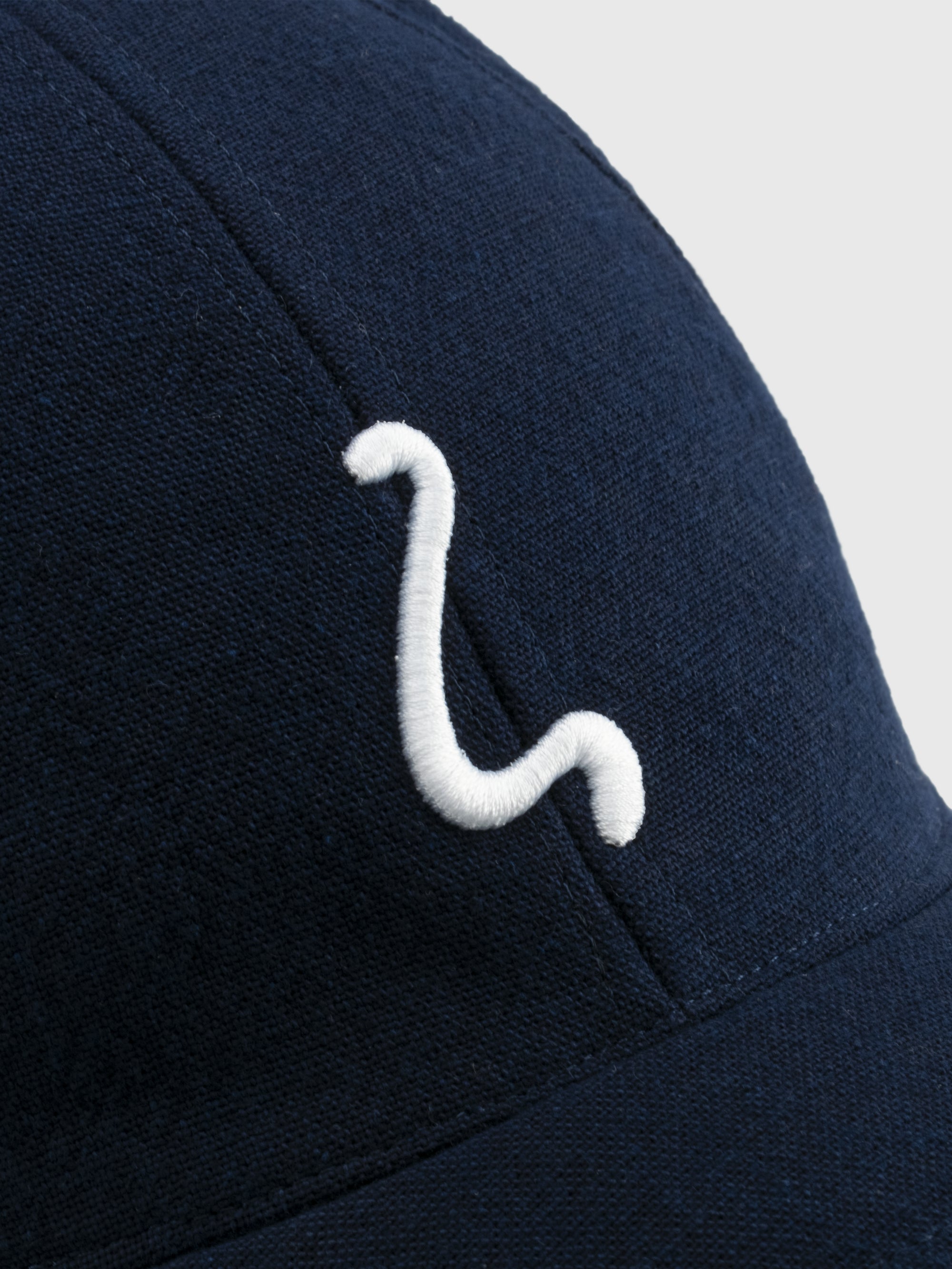 Navy blue cap with a white logo on a light gray background
