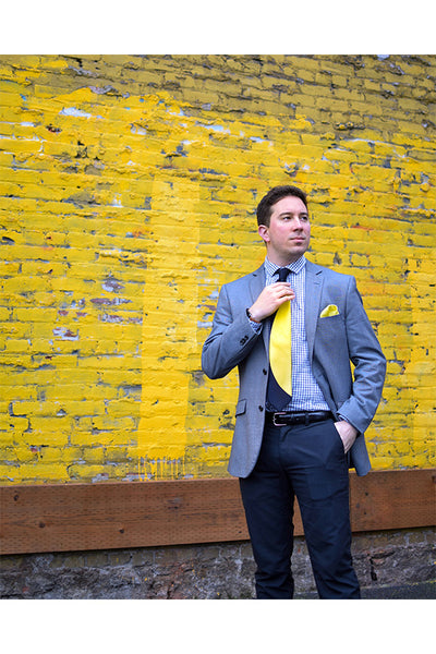 Lesovs Black and Yellow Eclipse Tie in front of yellow wall