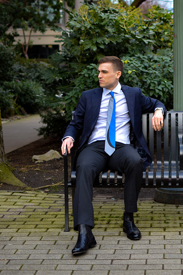 Lesovs Blue Black and Gray Curves Silk Tie with man sitting on bench